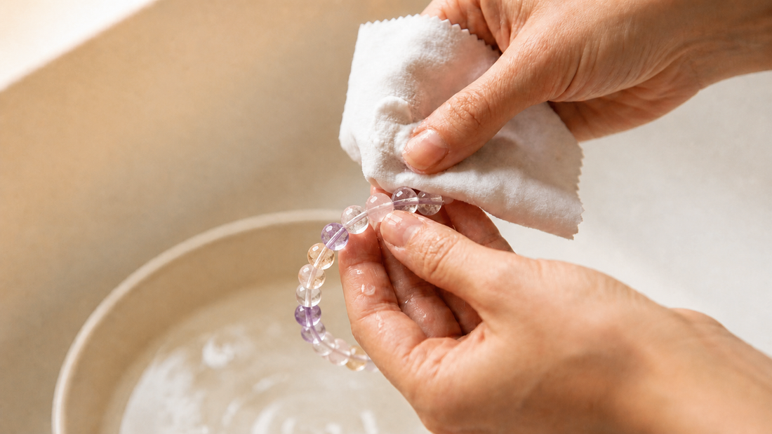 Hands gently wiping a crystal bracelet with a soft cloth above a cream bowl