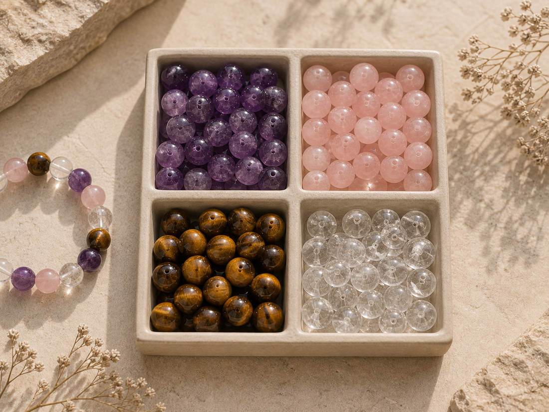 Amethyst, rose quartz, tiger's eye, and clear quartz bracelet beads arranged in a four-compartment tray