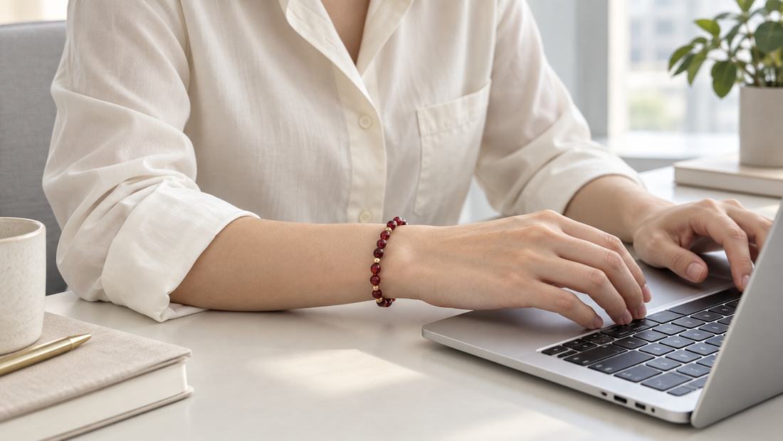 Professional wearing a low-profile red crystal bracelet while working on a laptop