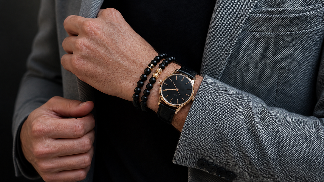 Man wearing two black crystal bead bracelets beside a gold-tone watch with a gray suit jacket