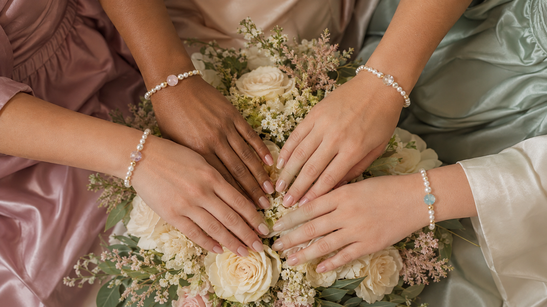 Four bridesmaids wearing coordinated pearl and gemstone bracelets around an ivory wedding bouquet