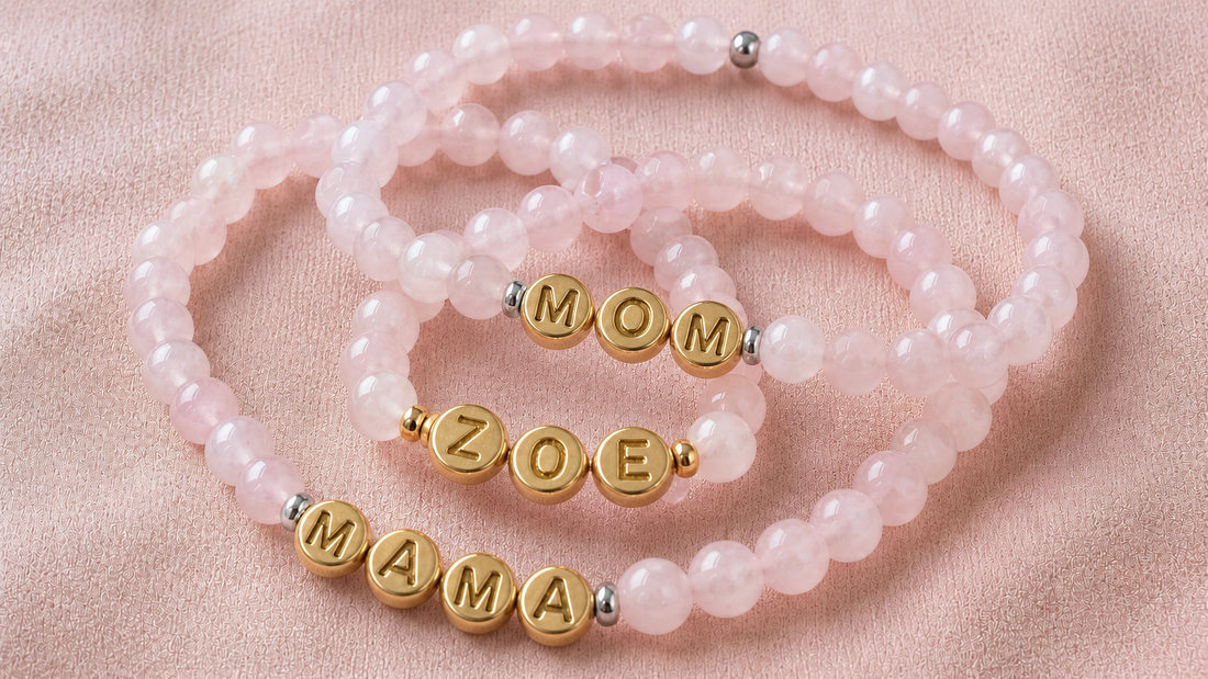 Three rose quartz name bracelets spelling MOM, ZOE, and MAMA with round gold metal letter beads and mixed-metal spacers