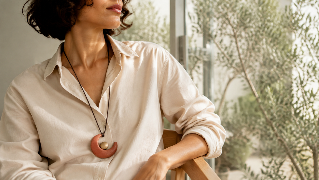 AI-generated styling illustration of a terracotta crescent pendant worn with a beige open-collar shirt